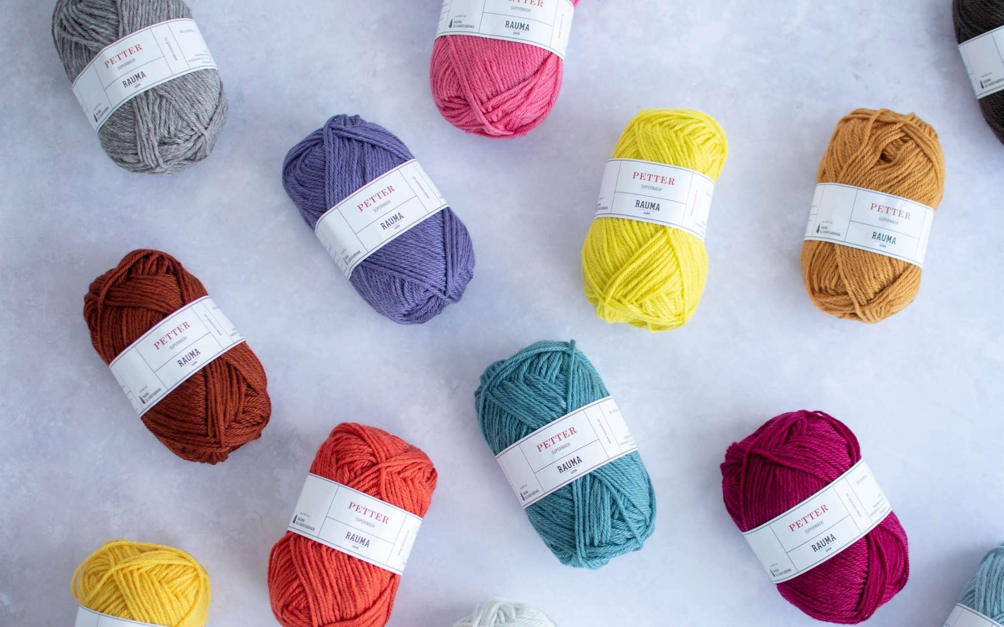 balls of brightly coloured yarn lie scrattered on a pale grey surface