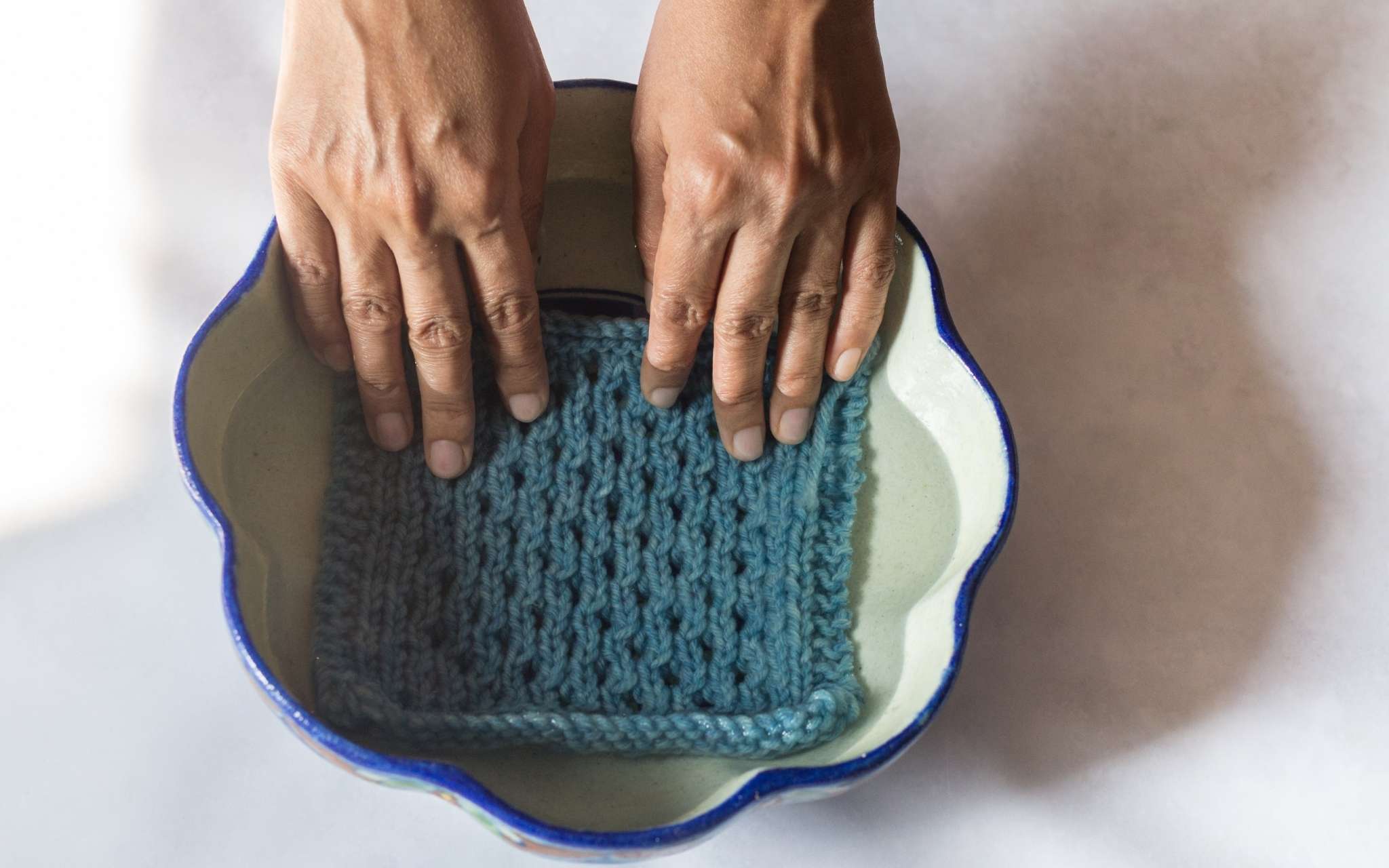 A swatch is being held during water in a small bowl with scalloped shaped edges.