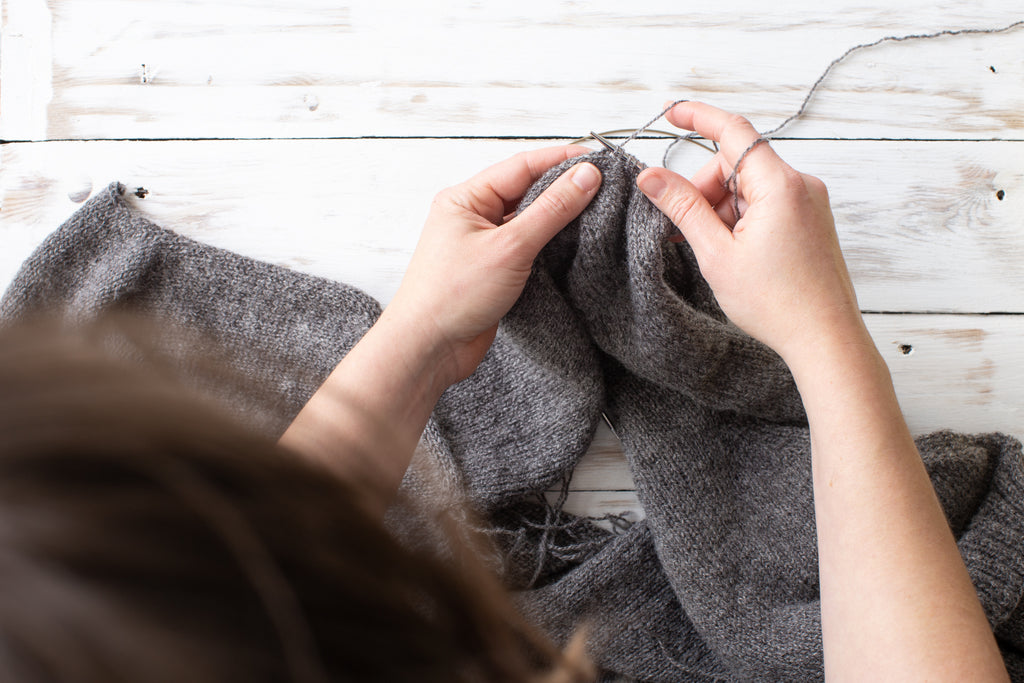 Image of an pair of white skinned hands picking up and knitting stitches