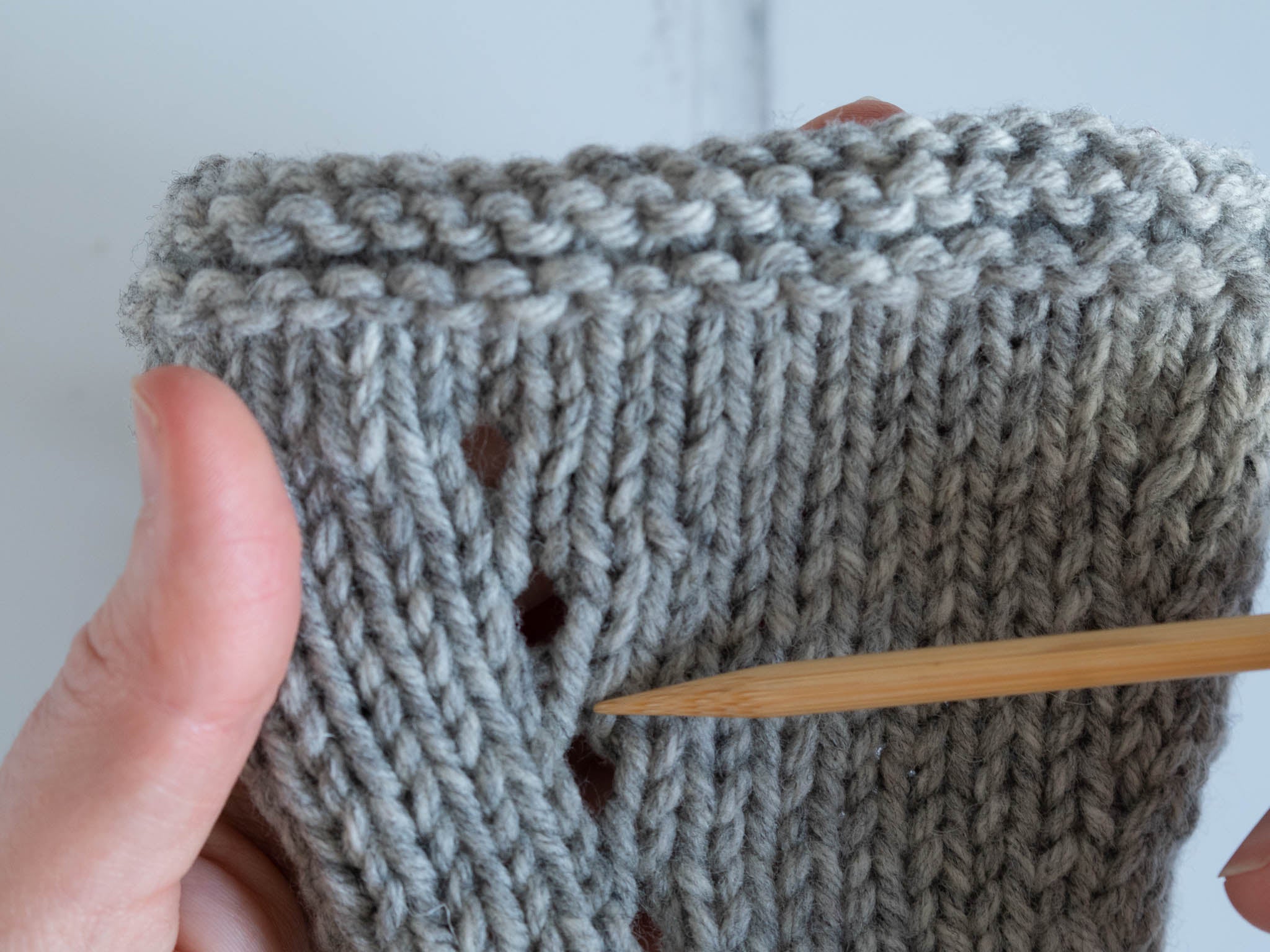 yarn over increases shown on a grey knitted swatch