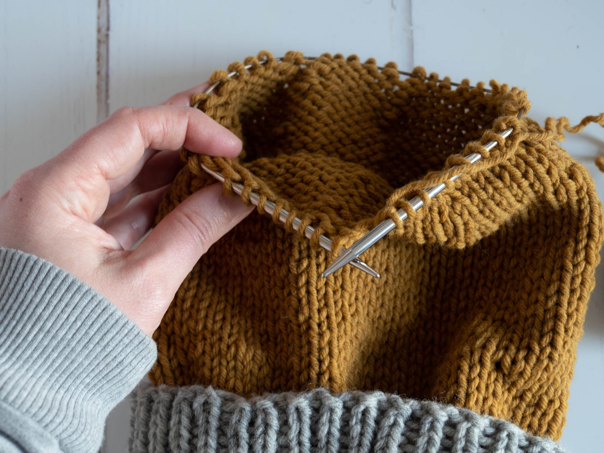 a grey and gold hat work in progress on a 16" circular needle