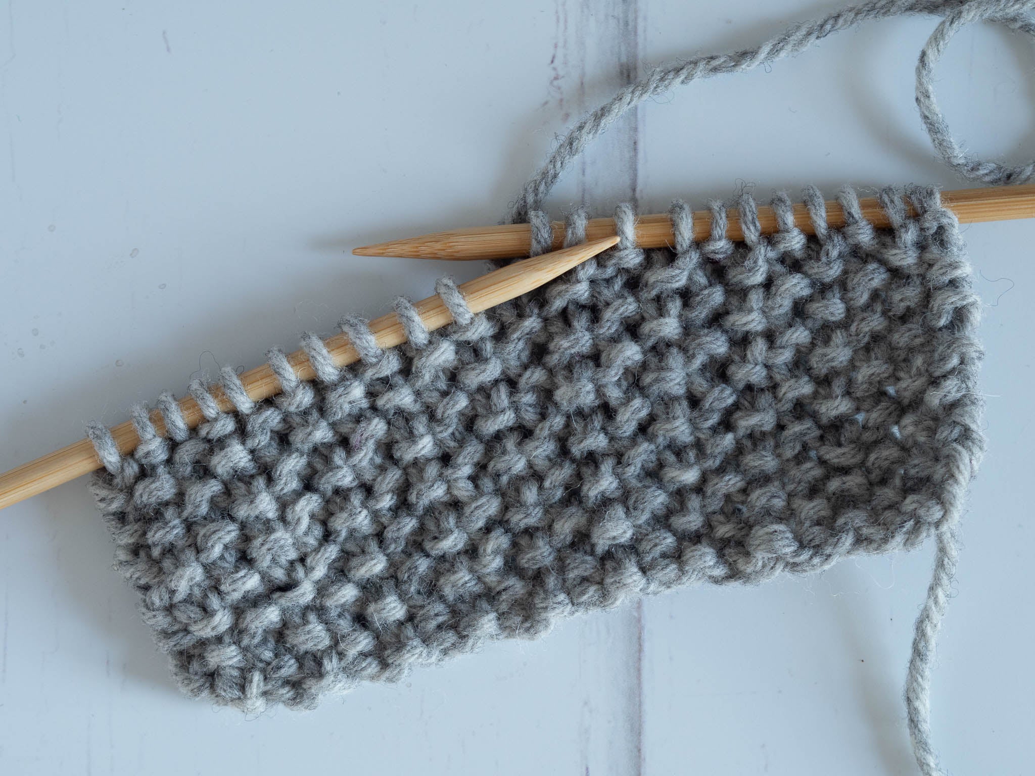 a grey seed stitch swatch on the needles