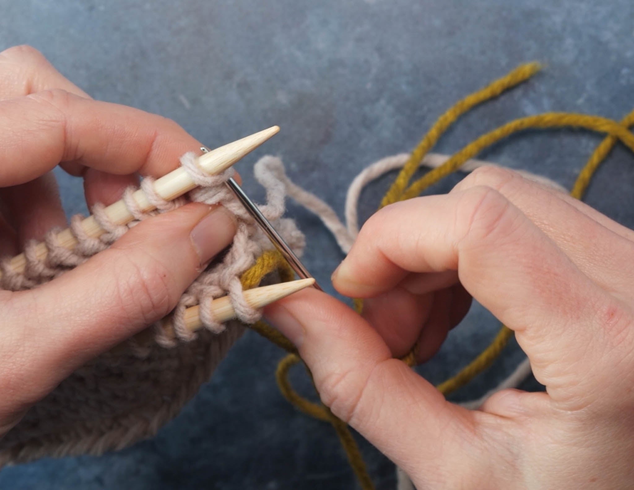 Insert tapestry needle into the first st on the back needle knit wise.