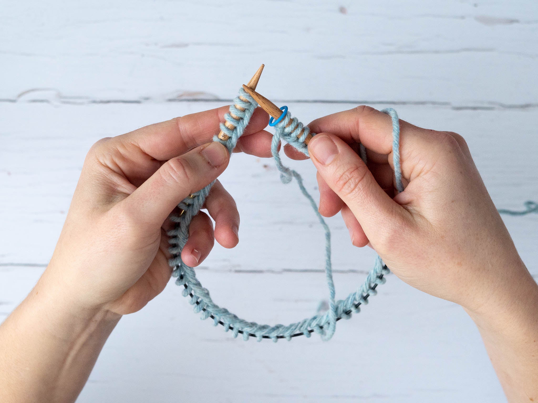 close up of the needle tips with a stitch marker on the right needle tip