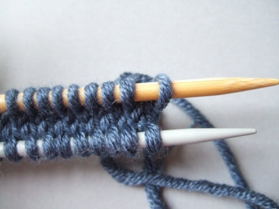 stockinette strip with a metal needle along the bottom and a bamboo needle along the top