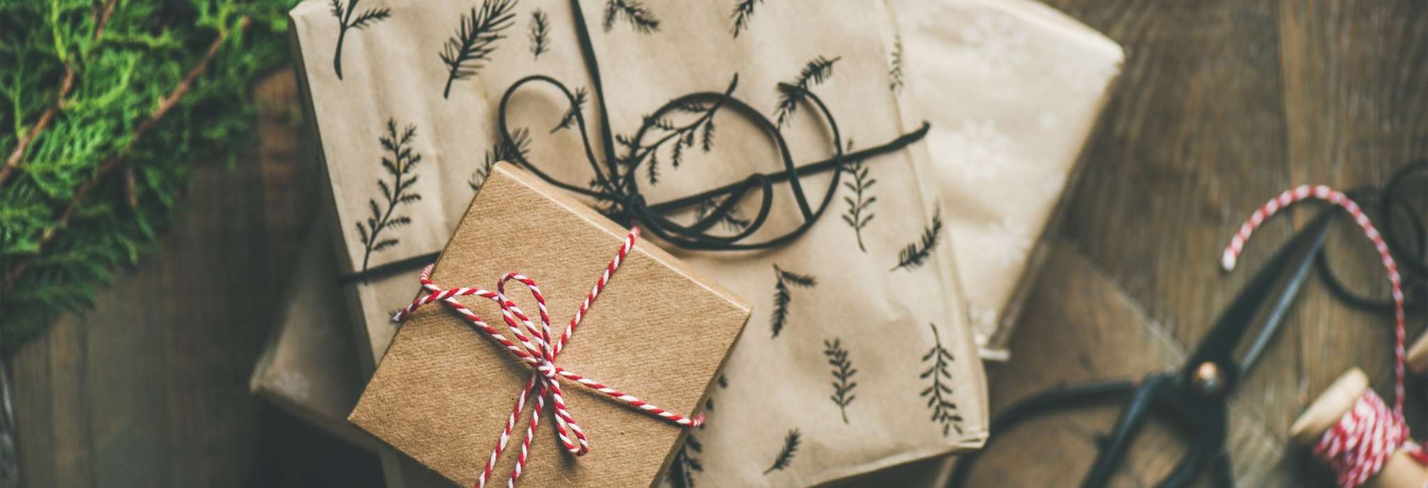 a pile of presents wrapped in brown paper and tied with red and white string are piled together on a wooden surface.