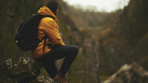 man resting on a rock while hiking