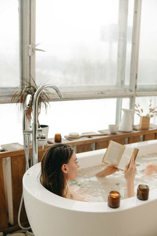 woman relaxing in bathtub reading a book