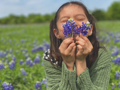 girl sniffing purple flowers