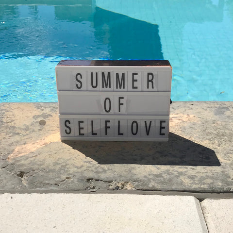Board in front of a pool that says Summer of Self-Love