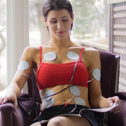 woman using with electronic stimulator machine while sitting down - Tone-A-Matic Electronic Muscle Stimulators in Canada