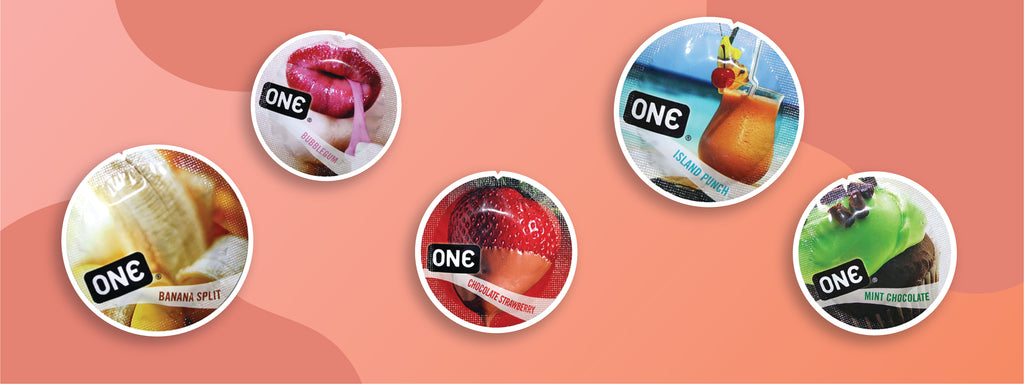 Five ONE Condom wrappers each with fruit on them. Flavorwaves condoms are flavored condoms that can be used for oral or penetrative sex. Flavors shown are banana split, bubblegum, chocolate strawberry, island punch, and mint chocolate.
