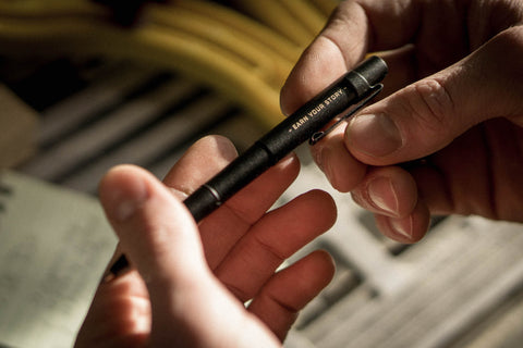 tactical pen in persons hands looking at it