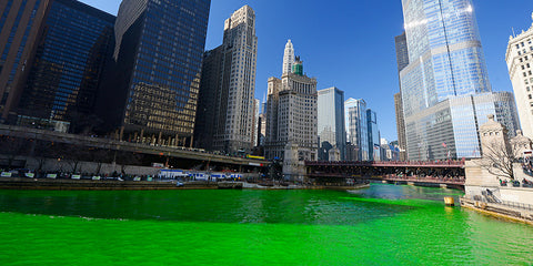 St. Patrick's Day in downtown Chicago. The river is dyed green and the tall skyscrapers loom over a passing parade.