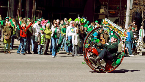 A man rides a kind of unicycle, covered almost completely in green and shamrocks during the Cleveland St. Patrick's Day Parade.