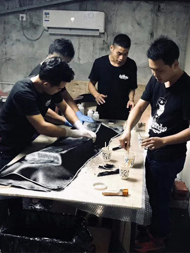 Crazy Grandpa Garage team applying the carbon fiber sheet to the car spoiler mold.