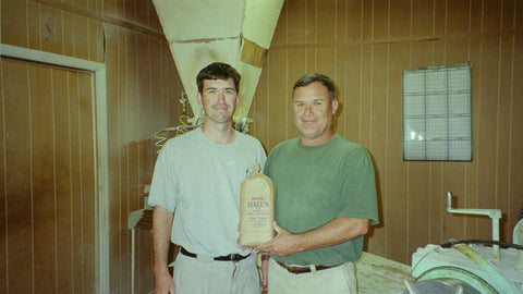 Photograph image of Jason Hall and Hannon Hall, Jr. holding a bag of Hall's Cornmeal.