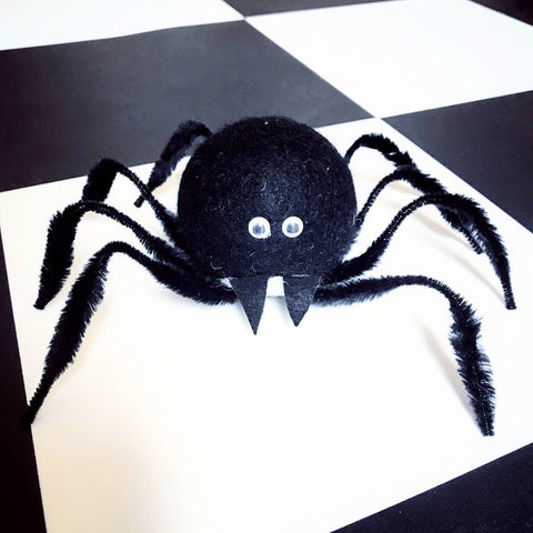 a cute black spider made with a repurposed dryer ball and some pipe cleaners