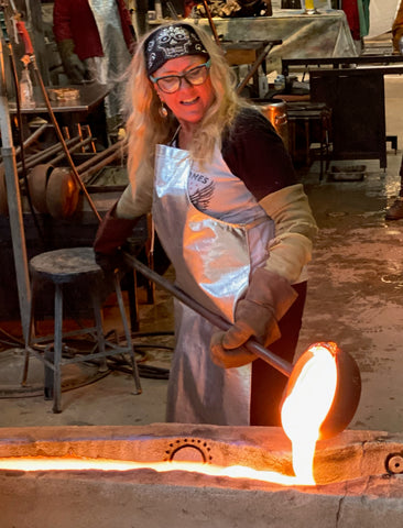 glass artist Susan Gott pouring molten glass into a sand mold