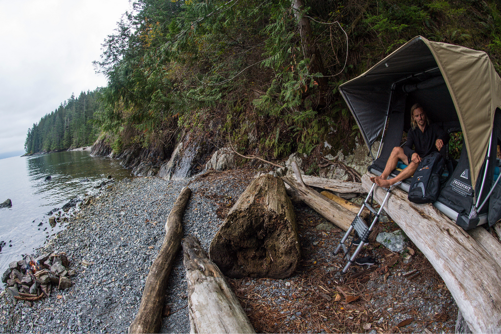 Mark Abma sitting inside a tent on the shore of Gambrier Island looking over Howe Sound