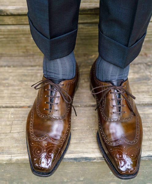 man wearing brown wingtip oxfords with a mirror shine and dark trousers with grey dress socks