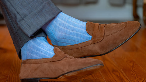 pastel blue dress socks with light brown suede loafers and a grey suit