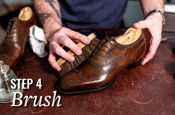 man using a horsehair brush to brush brown oxford dress shoes