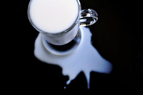 Glass mug of milk spilled on a counter or desk, leaving liquid rings
