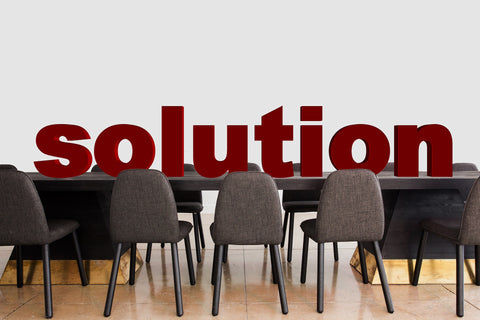 The word solution sitting on top of a desk with chairs 