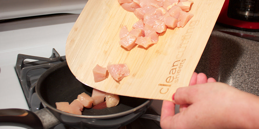 Using a CleanCutting Sheet to pour chicken into a pan.