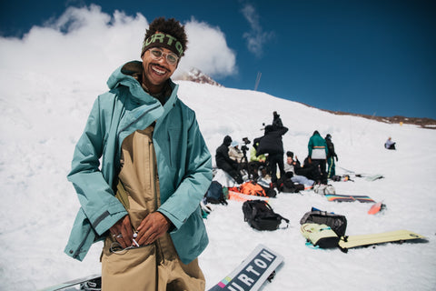 A picture of snowboarder Kody Williams smiling at the camera with a group of other snowboarders in the distance behind him.