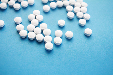 A picture of scattered white pills across a bright blue backdrop.