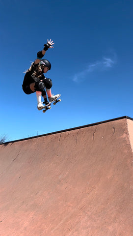 An image featuring Zoe catching air at the top of a half-pipe with a beautiful blue sky in the background.