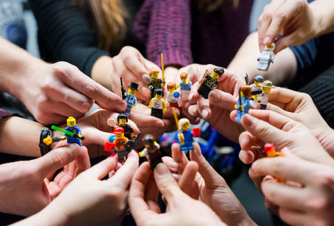 An image of children's hands holding up Lego figurines.
