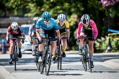 An image of Tori racing alongside other cyclists, all in spandex cycling gear on a city road.