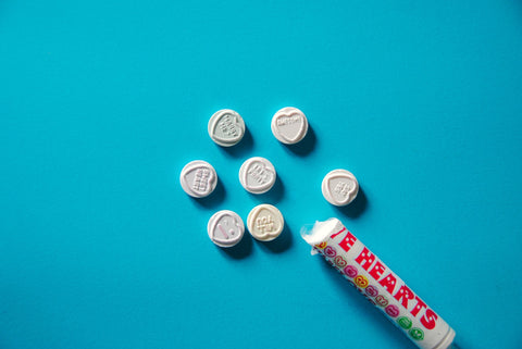 An image showing a roll of hard candies on a bright blue background, with some of the candies tumbling out.