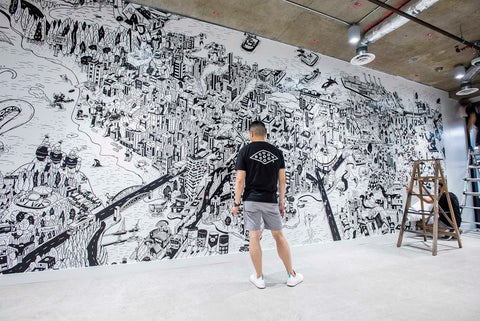 An image of Chairman Ting, facing away from the camera, as he surveys a giant black and white mural.