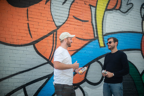 An image of Wize co-founders Max and Arnaud standing in front of a giant colorful mural.