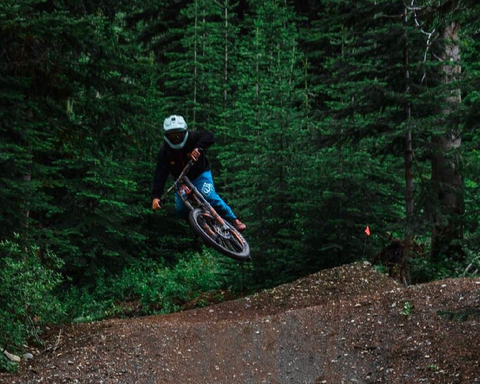 An image of Joe on his bike, going down a dirt trail with trees in the background.