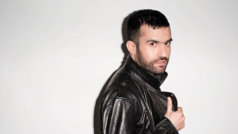 An image of a DJ in a black leather jacket against a white-grey backdrop.