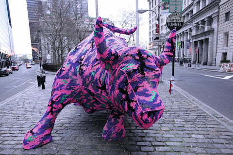 An image of the Wall Street bull statue, covered in crocheted yarn.