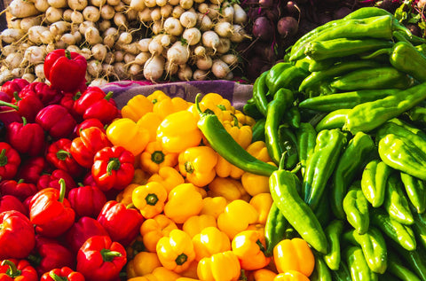 An image featuring a colorful collection of vegetables including red and yellow bell peppers.