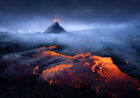 An image of a volcano in the distance with lava flowing in the foreground.