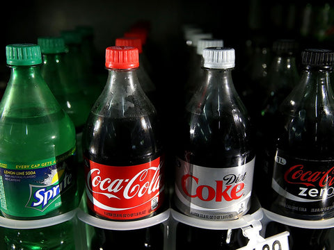 A row of soft drinks in a soda machine.