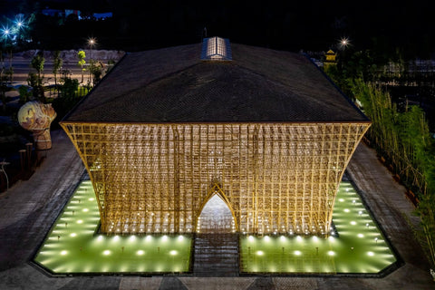 An image of the exterior of the Vietnamese Welcome Center at night, illuminated from below with lights coming out of a surrounding pool of water.