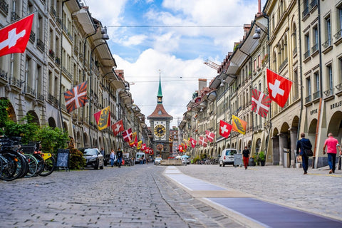 An image of a city street with Swiss flags hanging from several windows.