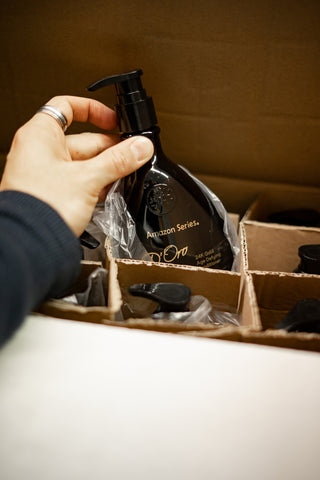 A bottle of the Amazon D'Oro 24K Gold shampoo is being lifted out of a bottle in Fine Edge Supply's Vancouver shop.