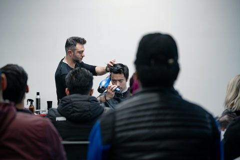 Professional barber, Ricardo, educating a crowd while using a Parlux blowdryer after a haircut
