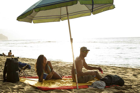 couple sitting on the beach using the parasheet beach blanket