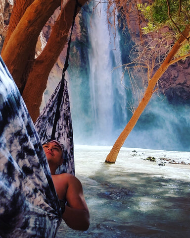 man hammocking in front of a waterfall in Havasupai